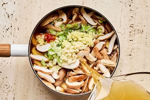 broth, mushrooms, green onions, ginger, garlic, soy sauce, chili paste, and fish sauce being added to a soup pot