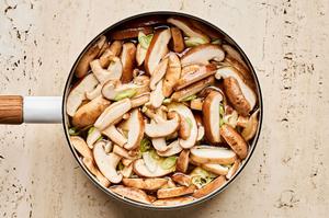 broth, mushrooms, green onions, ginger, garlic, soy sauce, chili paste, and fish sauce being cooked in a soup pot