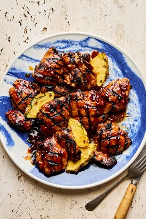 A plate of juicy huli huli grilled chicken served with fresh pineapple slices, a Hawaiian-style meal