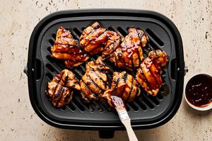 huli huli chicken being cooked on a grill and basted with extra sweet and smoky sauce