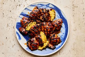 A plate of juicy huli huli grilled chicken served with fresh pineapple slices, a Hawaiian-style meal