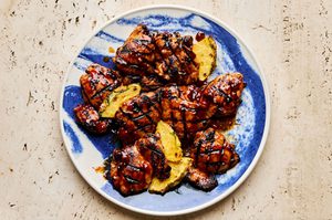 A plate of juicy huli huli grilled chicken served with fresh pineapple slices, a Hawaiian-style meal
