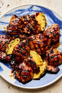 A plate of juicy huli huli grilled chicken served with fresh pineapple slices, a Hawaiian-style meal