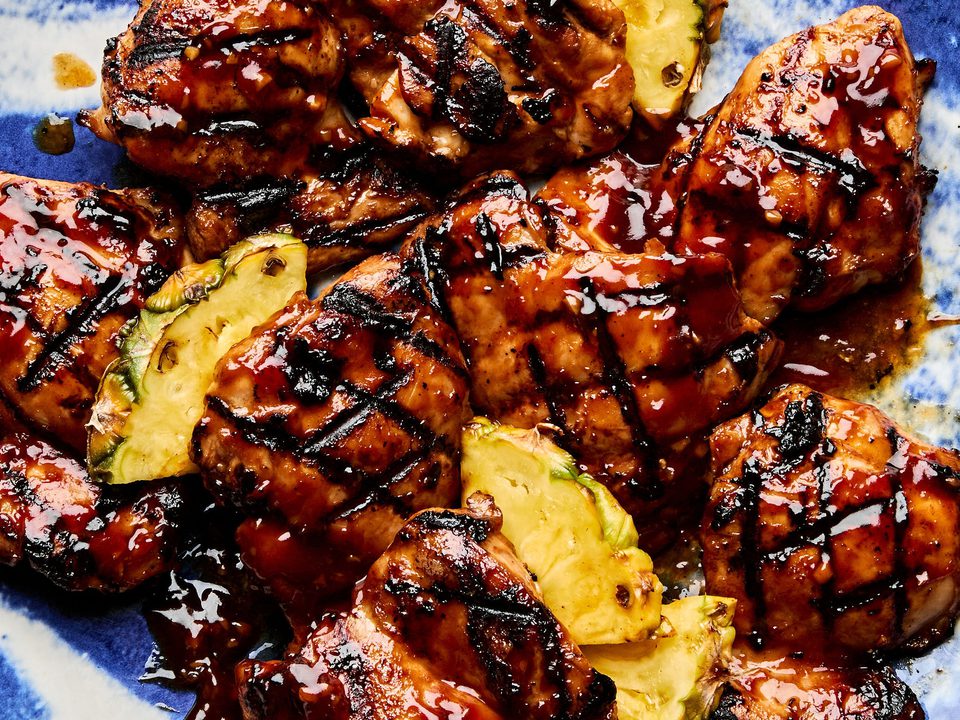 A plate of juicy huli huli grilled chicken served with fresh pineapple slices, a Hawaiian-style meal