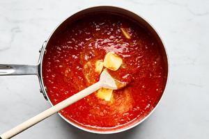jarred marinara sauce and butter being stirred together in a pot