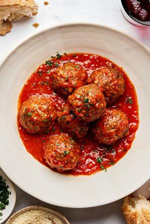 a bowl of Italian meatballs in marinara sauce made with ground beef and Italian sausage topped with parsley