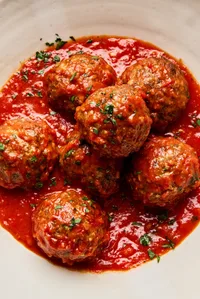 a bowl of Italian meatballs in marinara sauce made with ground beef and Italian sausage topped with parsley