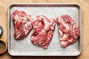lamb shoulder cut into 6 inch pieces being seasoned with salt and pepper