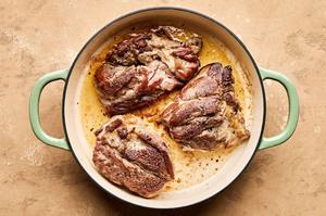 lamb shoulder seasoned with salt and pepper being browned in olive oil in a large pot