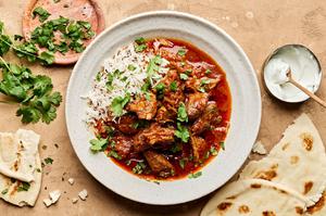 lamb curry on top of basmati rice and sprinkled with cilantro next to naan and greek yogurt for serving