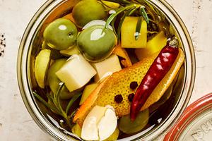 a jar of green olives and Gruyère marinated in garlic, orange, rosemary, peppercorn, dried chili and olive oil