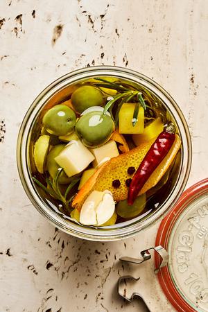 a jar of green olives and Gruyère marinated in garlic, orange, rosemary, peppercorn, dried chili and olive oil