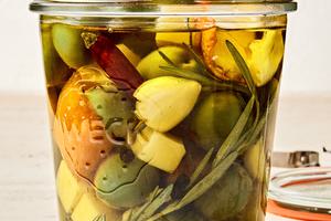 a jar of green olives and Gruyère marinated in garlic, orange, rosemary, peppercorn, dried chili and olive oil