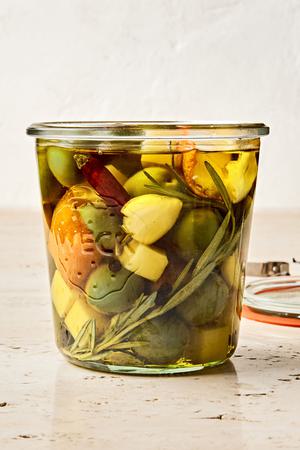 a jar of green olives and Gruyère marinated in garlic, orange, rosemary, peppercorn, dried chili and olive oil
