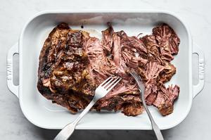 Mississippi pot roast made with au jus seasoning, a ranch packet, butter & pepperoncini being shredded with 2 forks