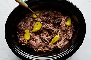 Mississippi pot roast in a slow cooker made with au jus seasoning, a ranch packet, butter, pepperoncini & pepperoncini juice