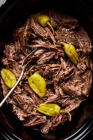 Mississippi pot roast in a slow cooker made with au jus seasoning, a ranch packet, butter, pepperoncini & pepperoncini juice