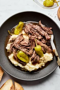 a bowl of Mississippi pot roast with pepperoncini served on top of mashed potatoes