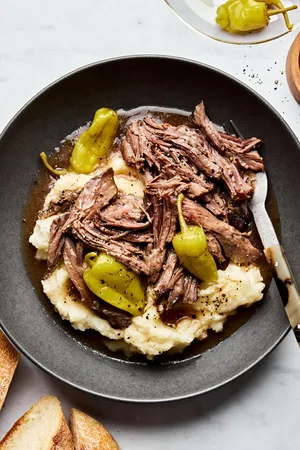 a bowl of Mississippi pot roast with pepperoncini served on top of mashed potatoes