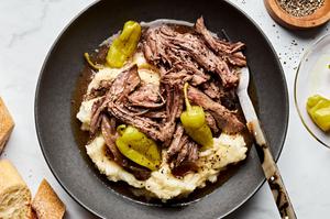a bowl of Mississippi pot roast with pepperoncini served on top of mashed potatoes
