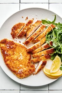 panko chicken sliced on a plate served with lemon wedges