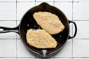 panko chicken covered in salt, pepper, eggs, flour & breadcrumbs being fried in vegetable oil