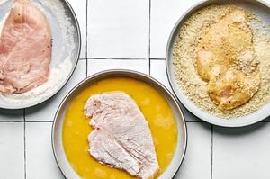 butterflied chicken seasoned with salt and pepper being dredged in flour, eggs and panko breadcrumbs