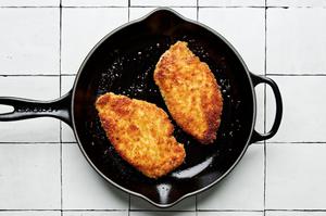 panko chicken covered in salt, pepper, eggs, flour & breadcrumbs being fried in vegetable oil