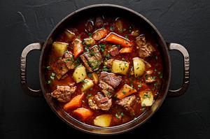 a pot of pork stew made with potatoes, carrots, onion, carrots, bacon, spices and tomato paste