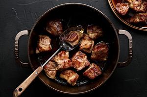 pork pieces being browned in a soup pot