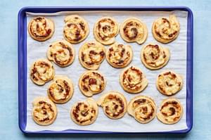 puff pastry pinwheels filled with cream cheese, swiss, caramelized onions, dijon & spices on a parchment lined baking sheet