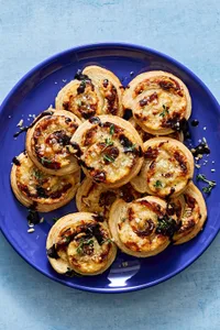 plate of puff pastry pinwheels filled with cream cheese, swiss, caramelized onions & spices drizzled with balsamic glaze