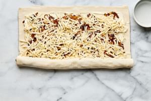 puff pastry filled with cream cheese, swiss, caramelized onions, dijon & thyme being rolled