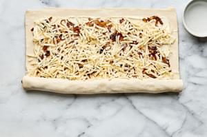 puff pastry filled with cream cheese, swiss, caramelized onions, dijon & thyme being rolled