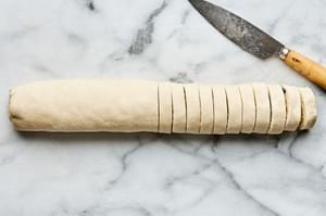 a rolled puff pastry filled with cream cheese, Swiss, caramelized onions, dijon & thyme being sliced into pinwheels