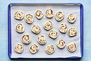 puff pastry pinwheels filled with cream cheese, swiss, caramelized onions, dijon & thyme on a parchment lined baking sheet