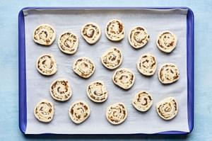 puff pastry pinwheels filled with cream cheese, swiss, caramelized onions, dijon & thyme on a parchment lined baking sheet