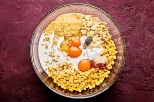 creamed corn, sweet corn, crushed crackers, butter, cream, eggs, sugar and spices being combined in a bowl