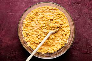creamed corn, sweet corn, crushed crackers, butter, cream, eggs, sugar and spices being combined in a bowl