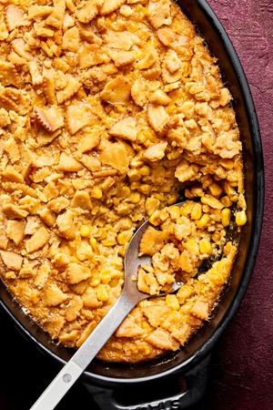 a dish of scalloped corn casserole topped with crushed ritz crackers
