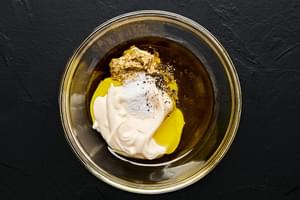 mayonnaise, olive oil, stone ground mustard, pickle juice, salt and pepper being mixed in a bowl