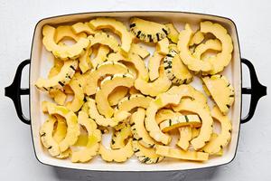 delicata squash sliced and tossed with olive oil and salt in a baking dish