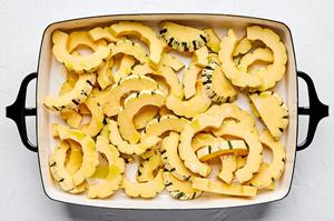 delicata squash sliced and tossed with olive oil and salt in a baking dish