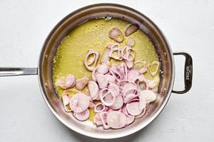 sliced shallots being cooked in melted butter in a skillet