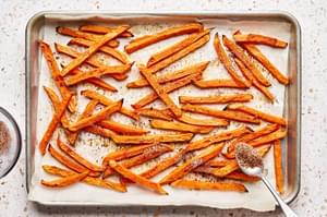 sweet potato fries being seasoned with brown sugar, garlic, chipotle chili powder, salt, & pepper