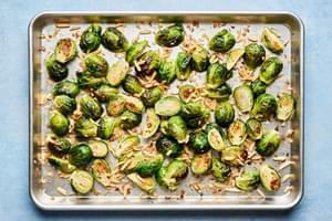 roasted brussels sprouts tossed with almonds, shallots, olive oil and salt on a baking sheet