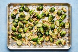 roasted brussels sprouts tossed with almonds, shallots, olive oil and salt on a baking sheet