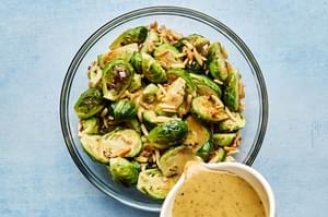 sweet and sour sauce being poured over roasted brussels sprouts