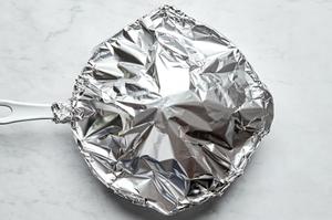 a whole head of cauliflower seasoned with olive oil, garlic, Italian seasoning, salt, paprika and pepper covered in foil