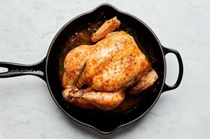 a whole roasted chicken seasoned with salt in a cast iron skillet